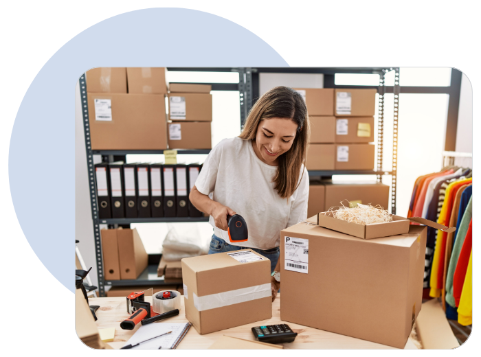 woman sticking a label on a box with computer next to her