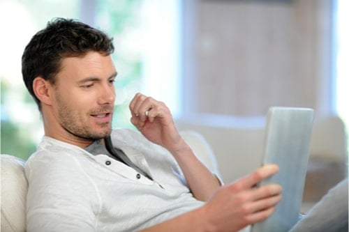 Man on sofa tracking parcel on tablet